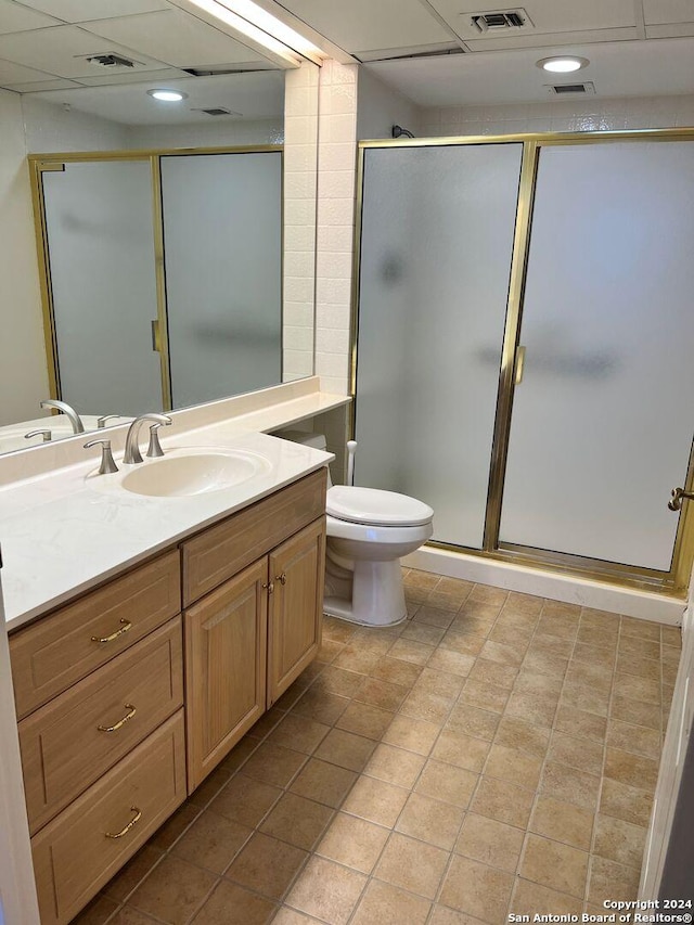 bathroom featuring a paneled ceiling, vanity, toilet, and walk in shower