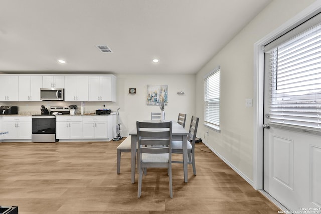 kitchen with appliances with stainless steel finishes, light hardwood / wood-style floors, and white cabinetry