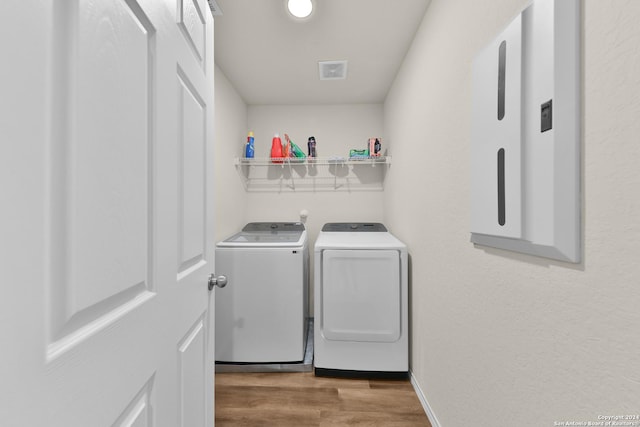 laundry room with washing machine and dryer and light hardwood / wood-style floors