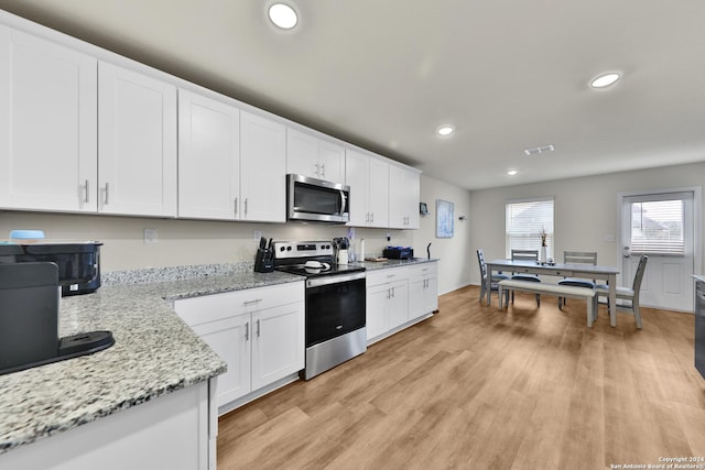 kitchen with light hardwood / wood-style flooring, stainless steel appliances, white cabinetry, and light stone counters