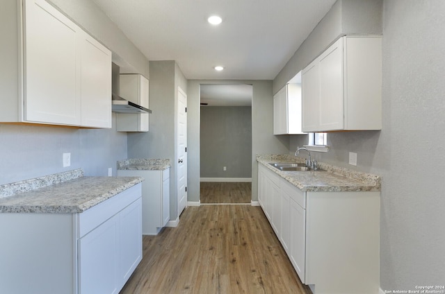 kitchen featuring white cabinetry, sink, and wall chimney range hood