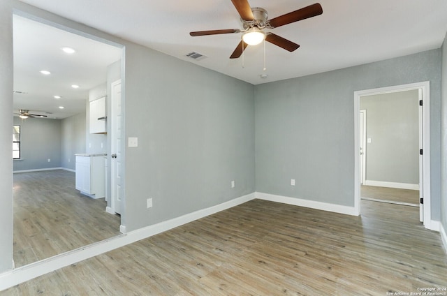 empty room with ceiling fan and light hardwood / wood-style flooring