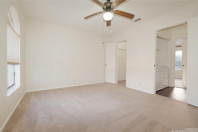 unfurnished bedroom with carpet flooring, a walk in closet, a closet, and ceiling fan