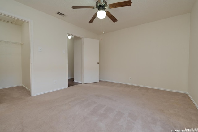 unfurnished bedroom featuring ceiling fan, a spacious closet, a textured ceiling, light colored carpet, and a closet