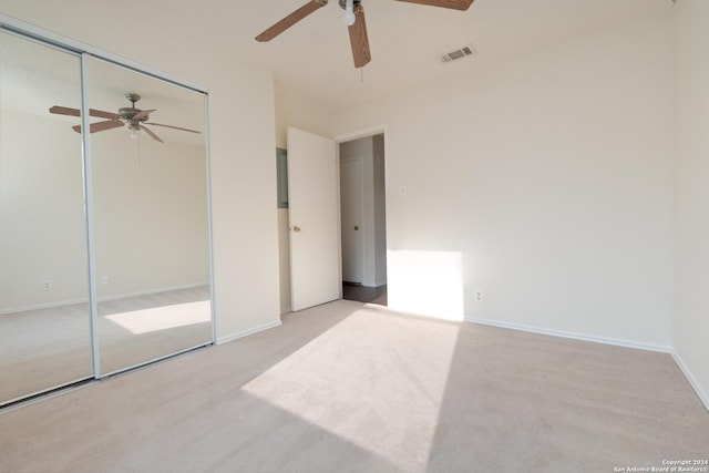 unfurnished bedroom with light colored carpet, a closet, and ceiling fan