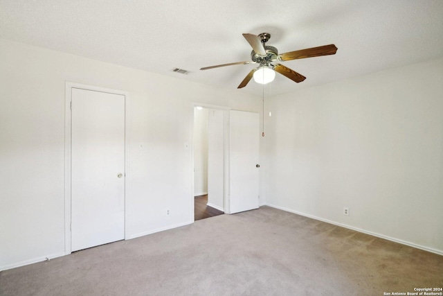 unfurnished bedroom featuring carpet, ceiling fan, and a textured ceiling