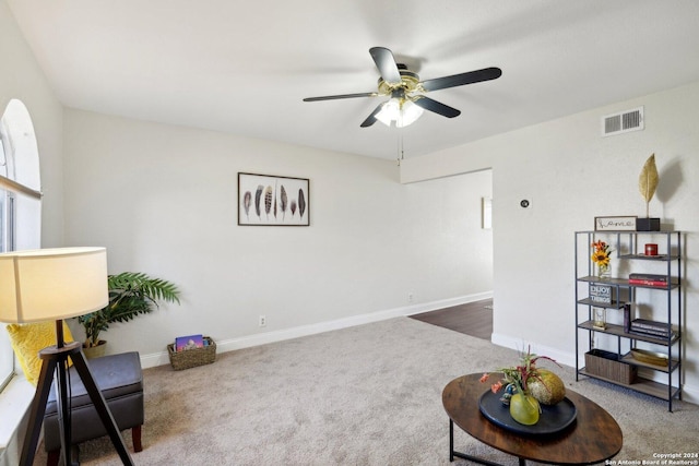 sitting room with ceiling fan and dark carpet