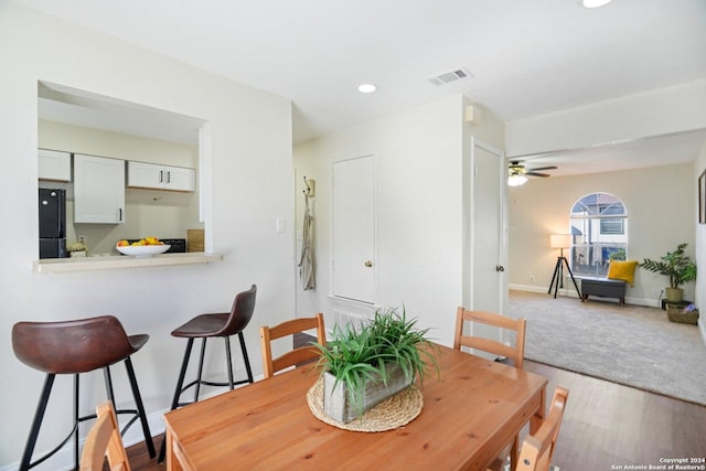 dining space with ceiling fan and light hardwood / wood-style flooring