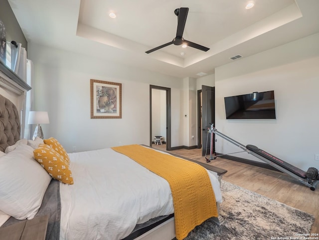 bedroom featuring a tray ceiling, ceiling fan, and light hardwood / wood-style flooring