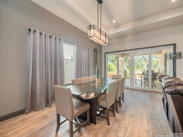 dining area featuring a raised ceiling and light wood-type flooring