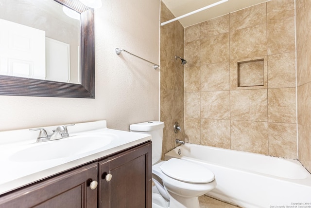 full bathroom featuring tiled shower / bath, vanity, and toilet