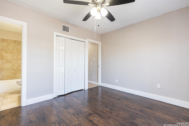 unfurnished bedroom featuring ceiling fan, dark hardwood / wood-style flooring, ensuite bathroom, and a closet