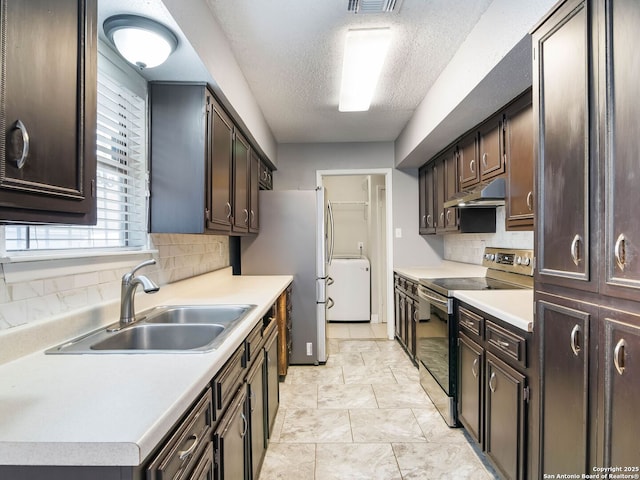 kitchen featuring sink, a textured ceiling, appliances with stainless steel finishes, dark brown cabinets, and washer / clothes dryer