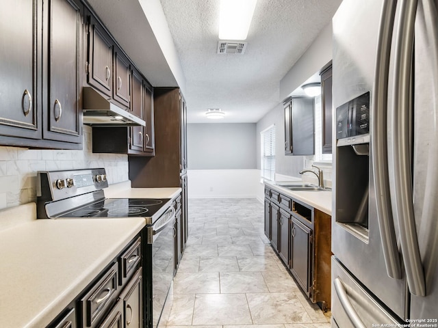 kitchen with backsplash, sink, a textured ceiling, appliances with stainless steel finishes, and dark brown cabinets