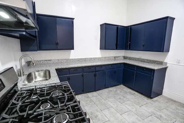 kitchen featuring exhaust hood, sink, light tile patterned floors, blue cabinetry, and gas stove