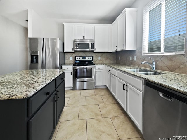 kitchen featuring decorative backsplash, appliances with stainless steel finishes, sink, light tile patterned floors, and white cabinets