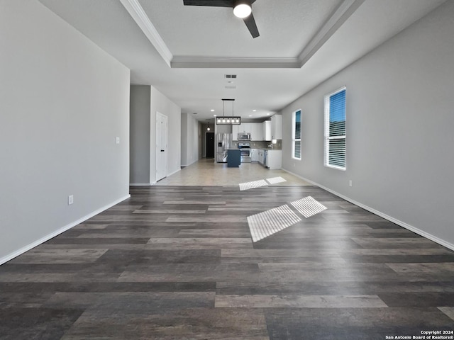 unfurnished living room featuring dark hardwood / wood-style flooring, a raised ceiling, ceiling fan, and crown molding