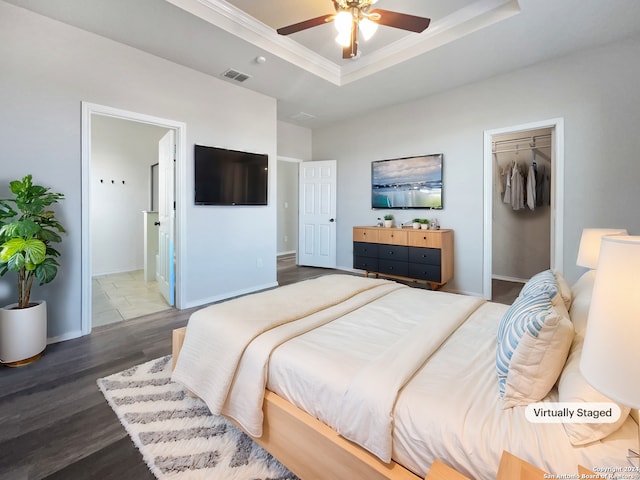 bedroom with ensuite bathroom, a tray ceiling, ceiling fan, hardwood / wood-style flooring, and a closet