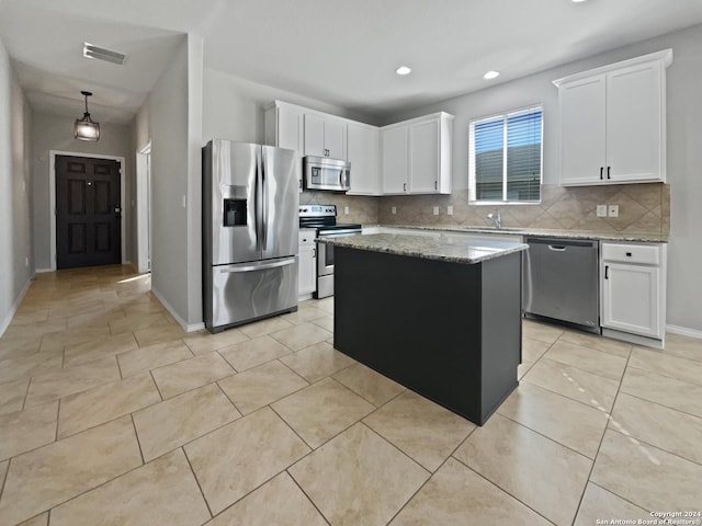 kitchen featuring a center island, light stone counters, white cabinetry, and appliances with stainless steel finishes