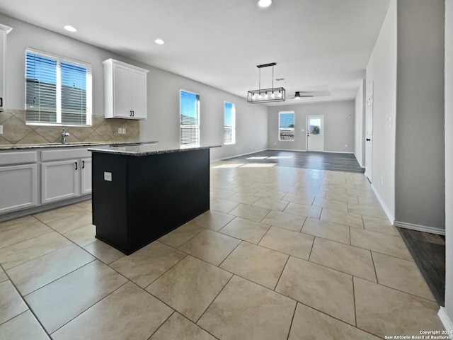 kitchen with pendant lighting, a center island, white cabinets, ceiling fan, and decorative backsplash