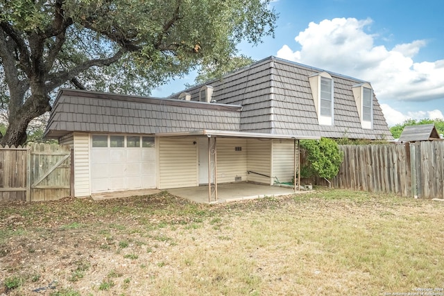 back of property with a yard, a patio, and a garage