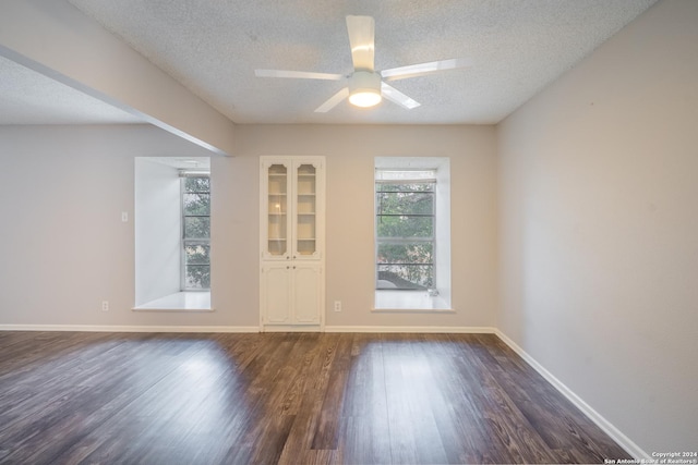 empty room with ceiling fan, dark hardwood / wood-style floors, and a textured ceiling