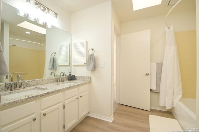 bathroom with wood-type flooring, vanity, a skylight, and shower / bathtub combination with curtain