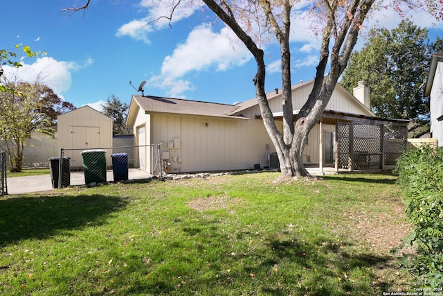 rear view of house featuring a lawn and a storage unit