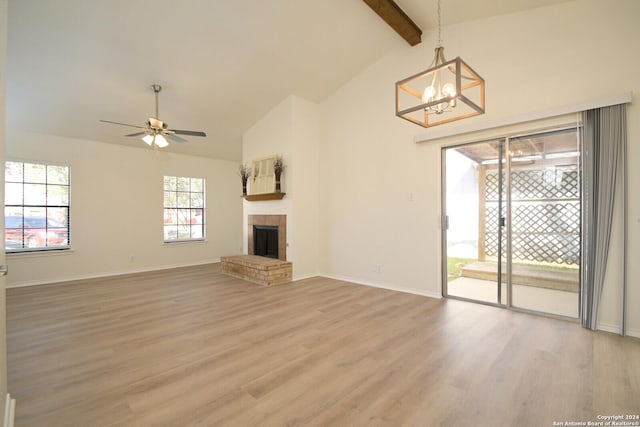 unfurnished living room featuring ceiling fan with notable chandelier, hardwood / wood-style floors, and lofted ceiling with beams