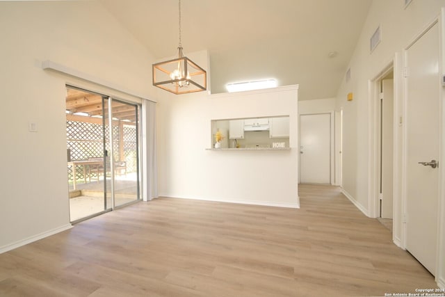 unfurnished dining area featuring an inviting chandelier, lofted ceiling, and light hardwood / wood-style flooring