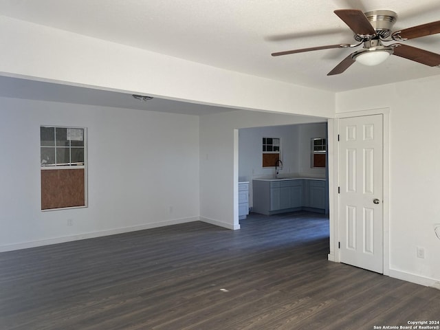 unfurnished living room with dark hardwood / wood-style floors, ceiling fan, and sink