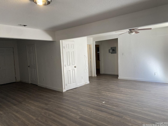 empty room featuring a textured ceiling, dark hardwood / wood-style floors, ceiling fan, and electric panel