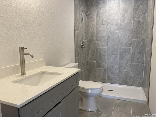 bathroom featuring vanity, toilet, and tiled shower