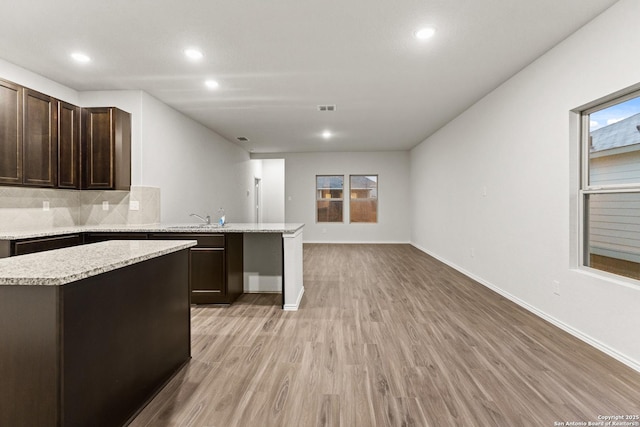 2659 Greenwell Ln, New Braunfels, TX 78130 - kitchen featuring open floor plan, recessed lighting, light wood-style flooring, dark brown cabinets, and decorative backsplash