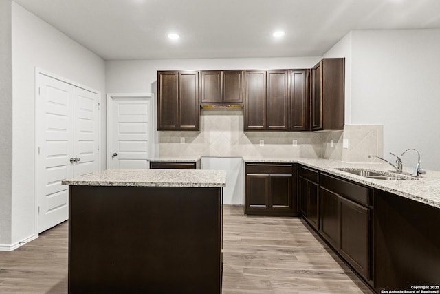 2659 Greenwell Ln, New Braunfels, TX 78130 - kitchen featuring dark brown cabinetry, backsplash, light wood finished floors, recessed lighting, and light stone counters