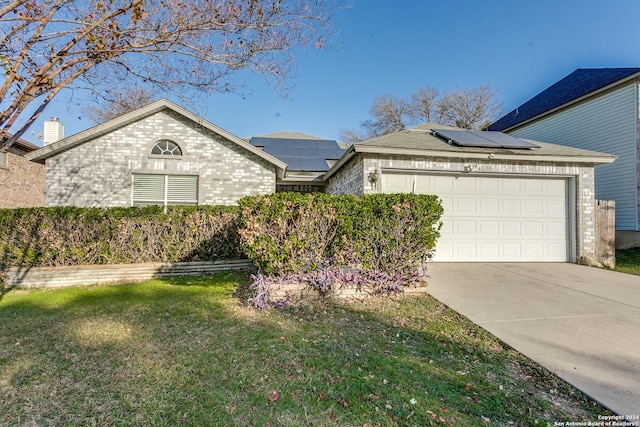 ranch-style home featuring a front lawn, a garage, and solar panels