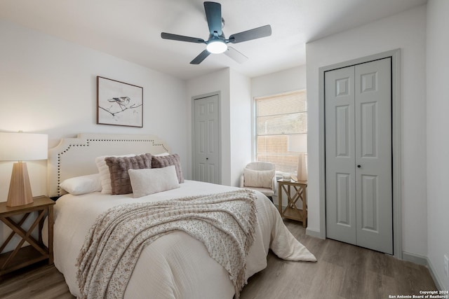 bedroom with wood-type flooring, two closets, and ceiling fan