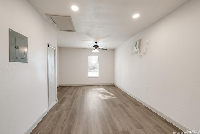 empty room featuring hardwood / wood-style flooring, ceiling fan, a wall mounted air conditioner, and electric panel