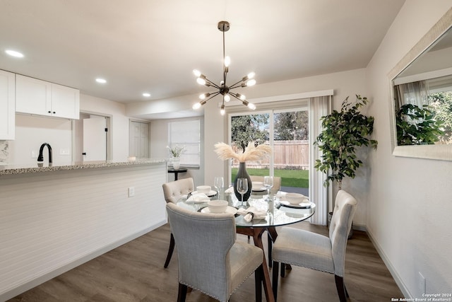 dining area with sink, dark wood-type flooring, and a chandelier