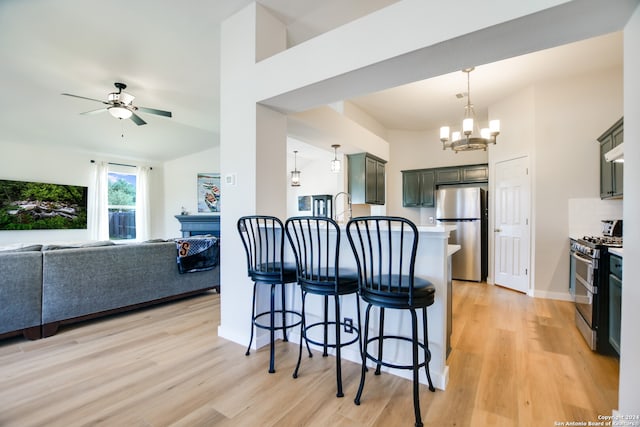 kitchen with ceiling fan with notable chandelier, tasteful backsplash, appliances with stainless steel finishes, and light hardwood / wood-style flooring