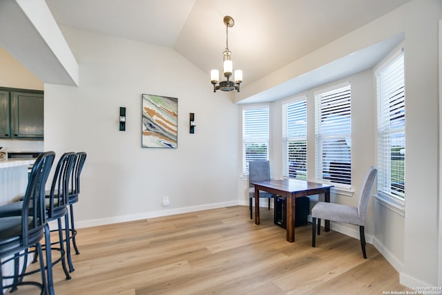 dining space featuring light hardwood / wood-style floors, vaulted ceiling, and a notable chandelier