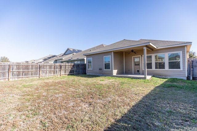 rear view of house with ceiling fan, a yard, and a patio