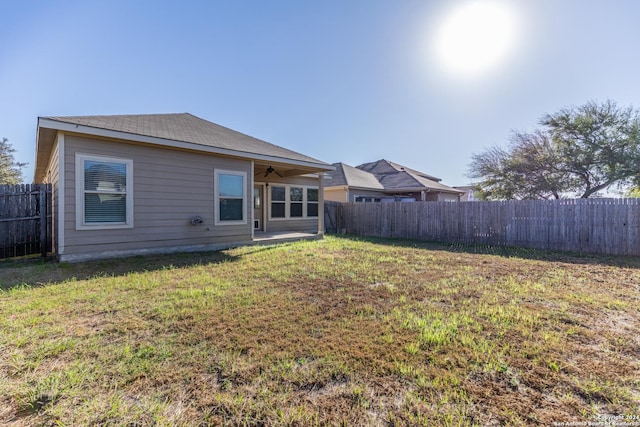 back of house with a lawn and ceiling fan