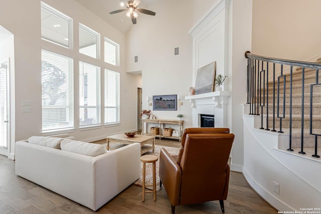 living room with a fireplace, wood-type flooring, a wealth of natural light, and ceiling fan