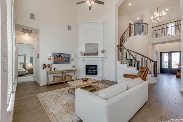 living room featuring french doors, ceiling fan with notable chandelier, hardwood / wood-style floors, and a high ceiling