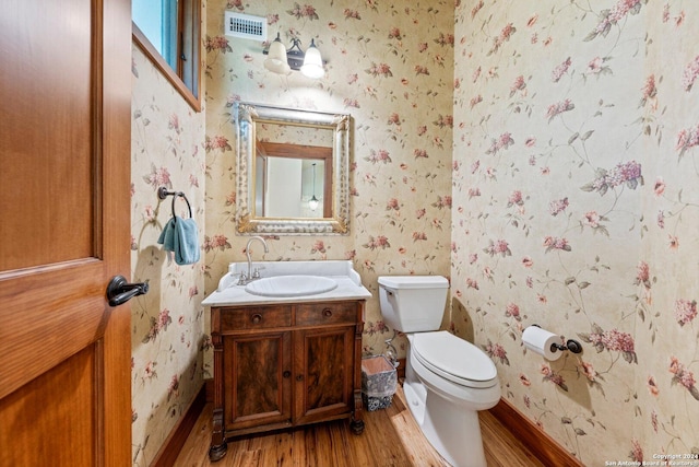 bathroom with toilet, vanity, and hardwood / wood-style flooring