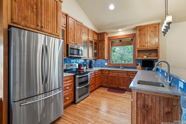 kitchen with sink, lofted ceiling, hanging light fixtures, and appliances with stainless steel finishes