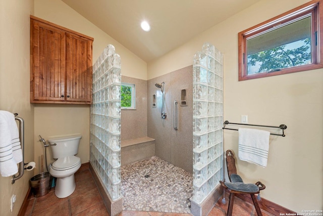 bathroom with tile patterned floors, toilet, vaulted ceiling, and tiled shower