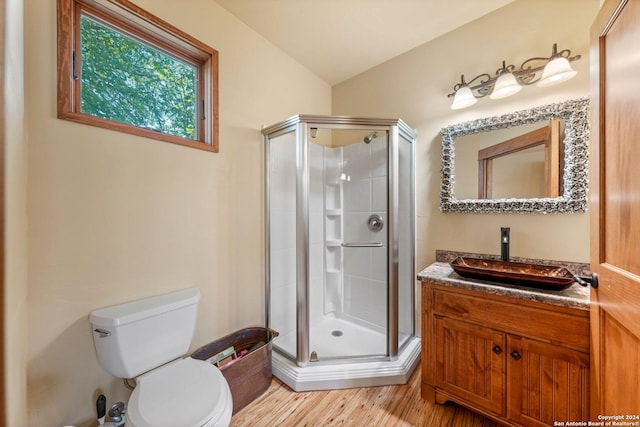 bathroom with hardwood / wood-style flooring, toilet, a shower with door, and vaulted ceiling