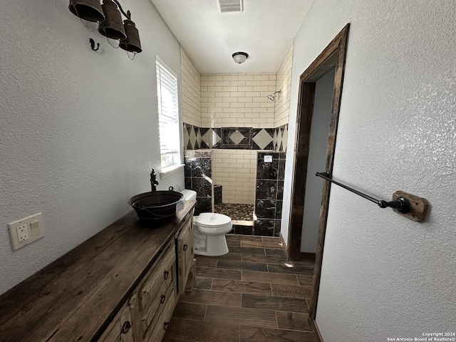 bathroom featuring toilet, a tile shower, and vanity